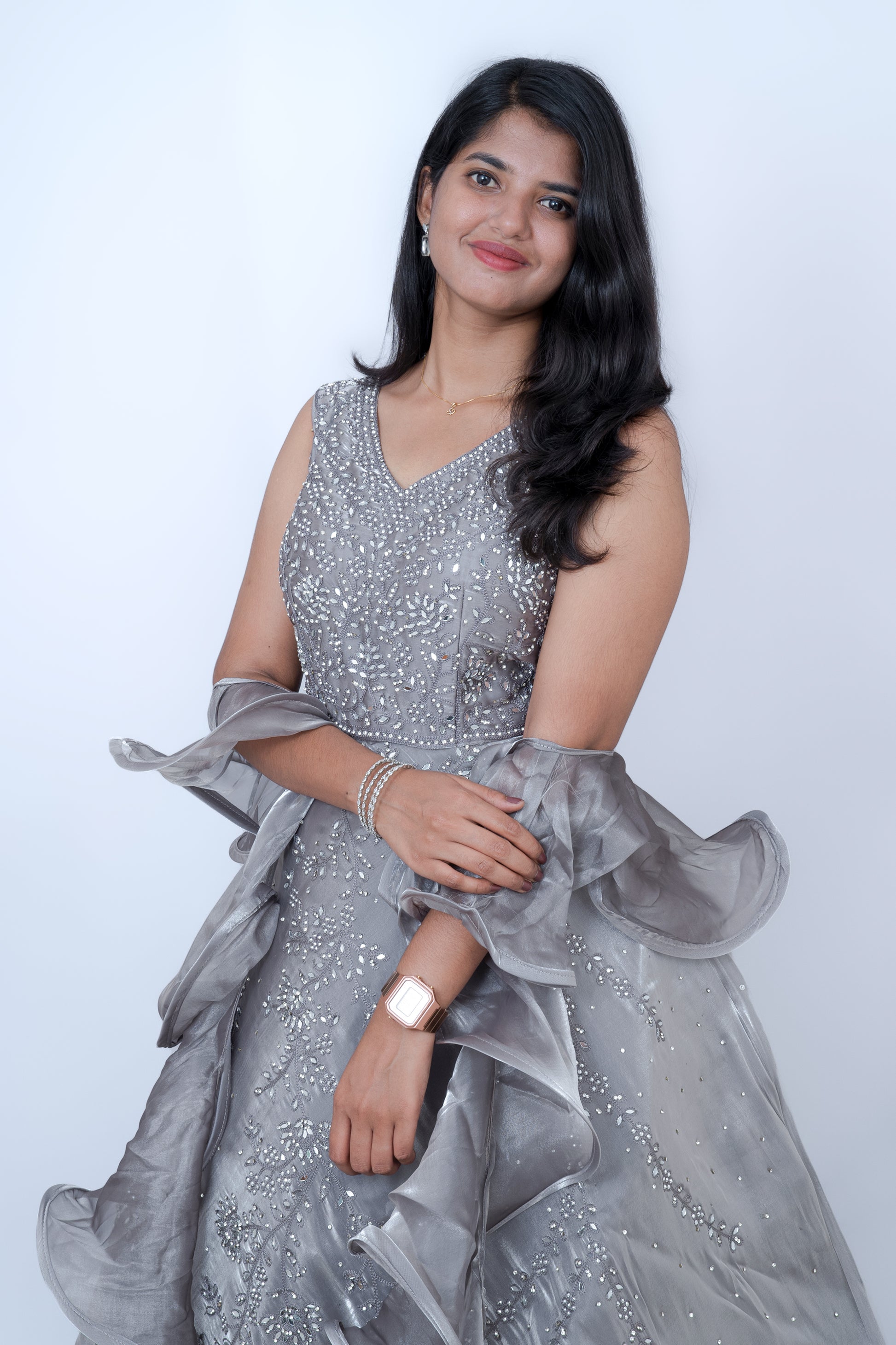 Woman wearing a silver glittery dress with ruffled sleeves against a white background